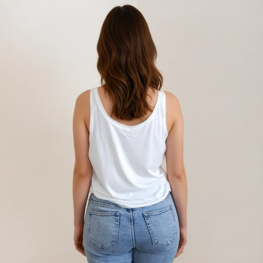 Person wearing light blue jeans and a white tank top against a plain background