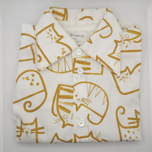 Folded shirt with gold cat pattern on a light gray background