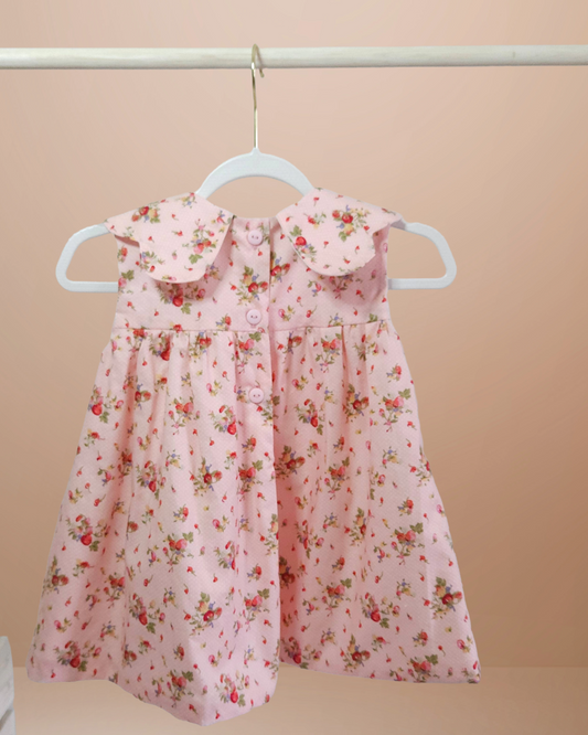 Back view of Pink floral dress on a hanger against a beige background