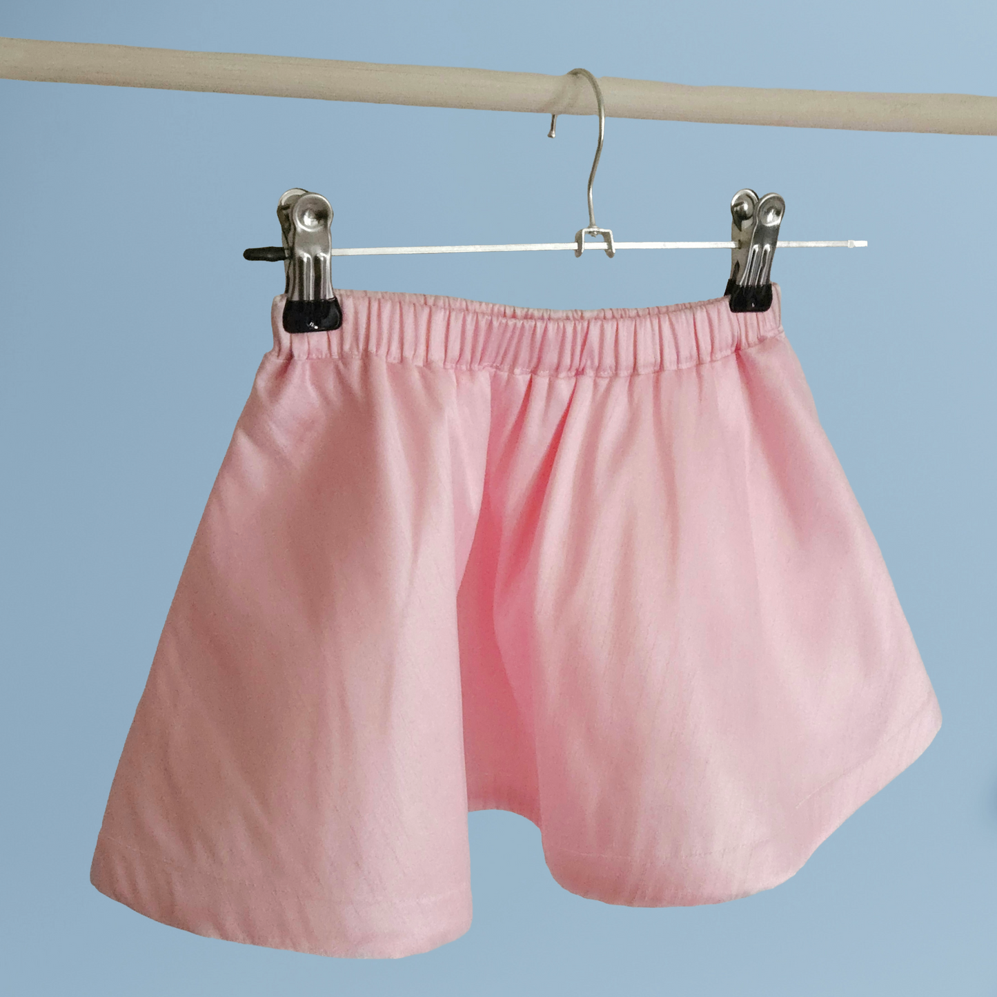 Pink skirt hanging on a hanger against a blue background