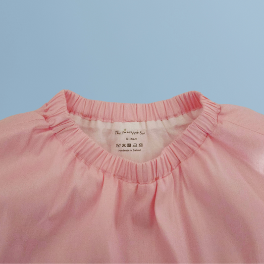 Close-up of a pink skirt with the brand label on a light blue background