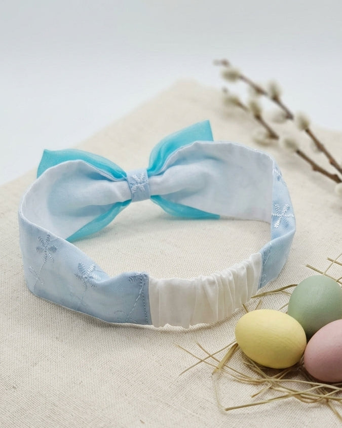 Baby headband with blue bow on a light background with Easter eggs decor