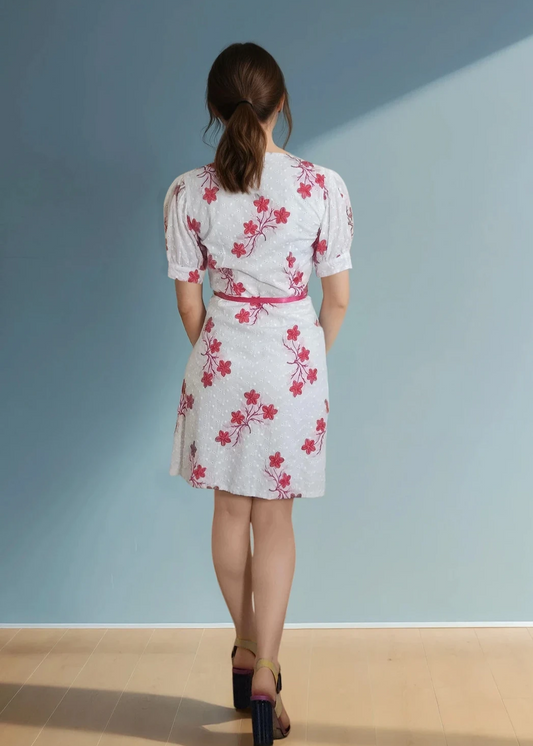 back of a white dress with pink floral embroderies and pink ribbon to close the dress