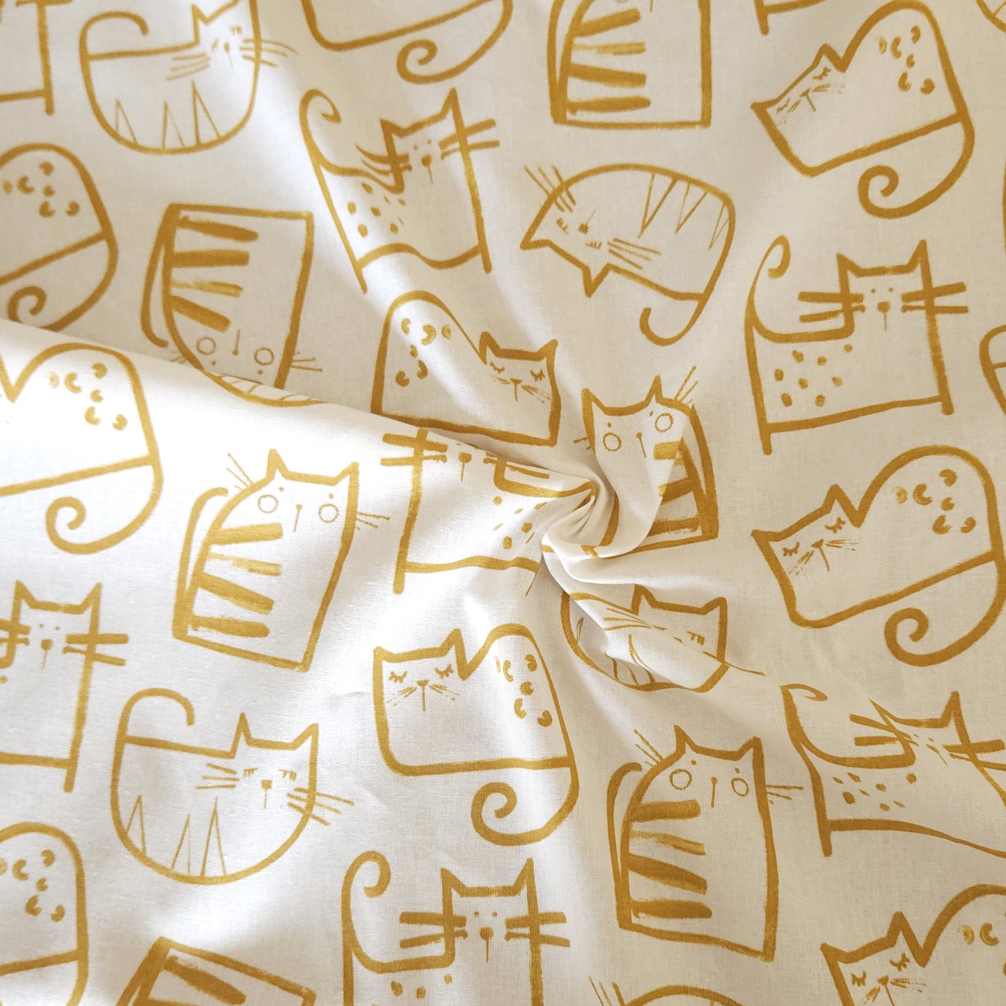 Gold cat illustrations on a beige fabric background