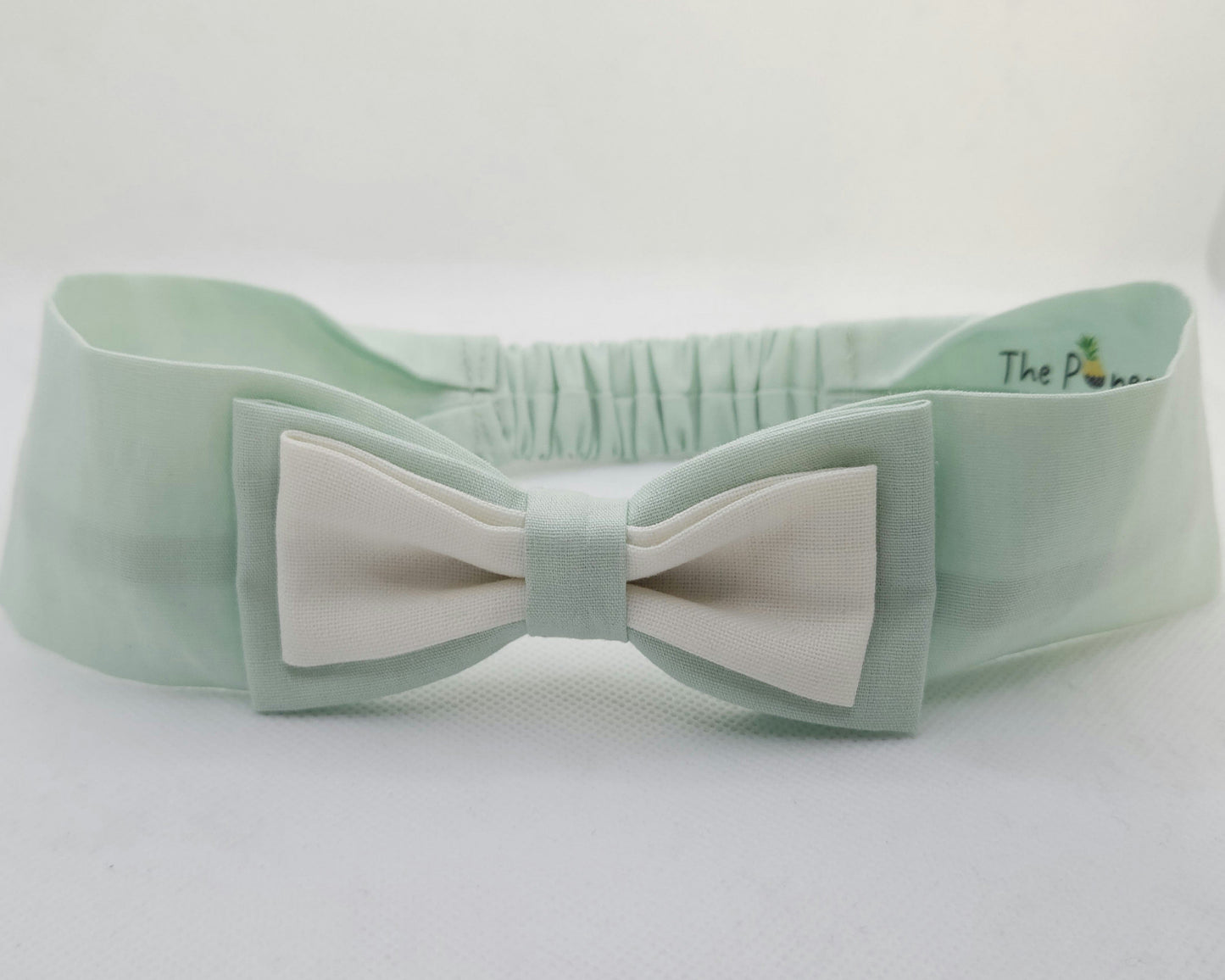 Light green headband with a white bow on a white background