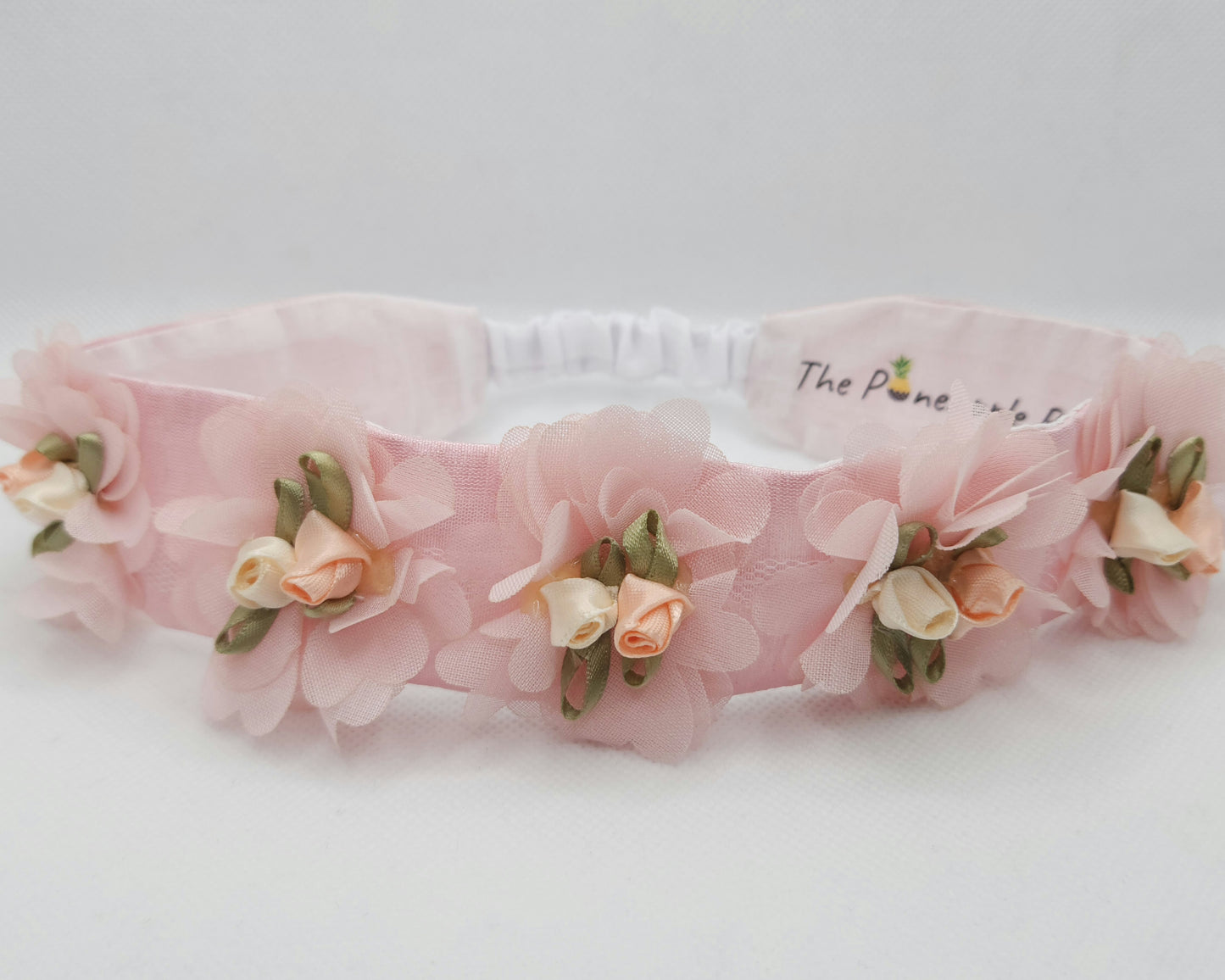 Pink floral headband on a white background