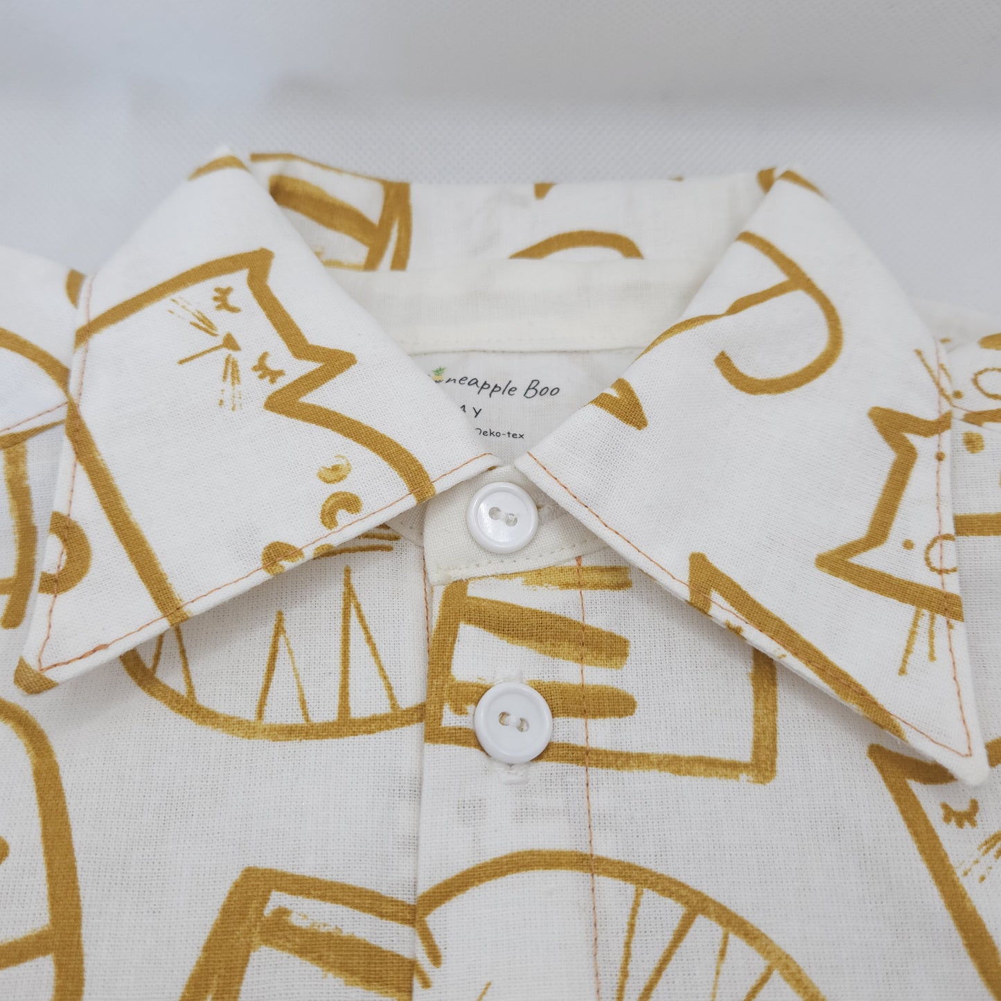 Close up of white shirt with gold cat pattern  on a white background