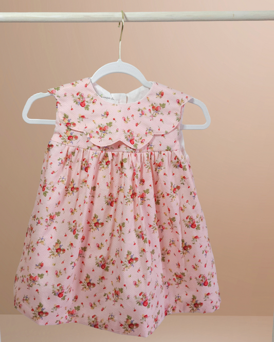 Pink floral dress on a hanger against a beige background