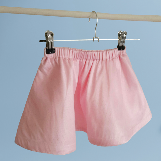 Pink skirt hanging on a hanger against a blue background