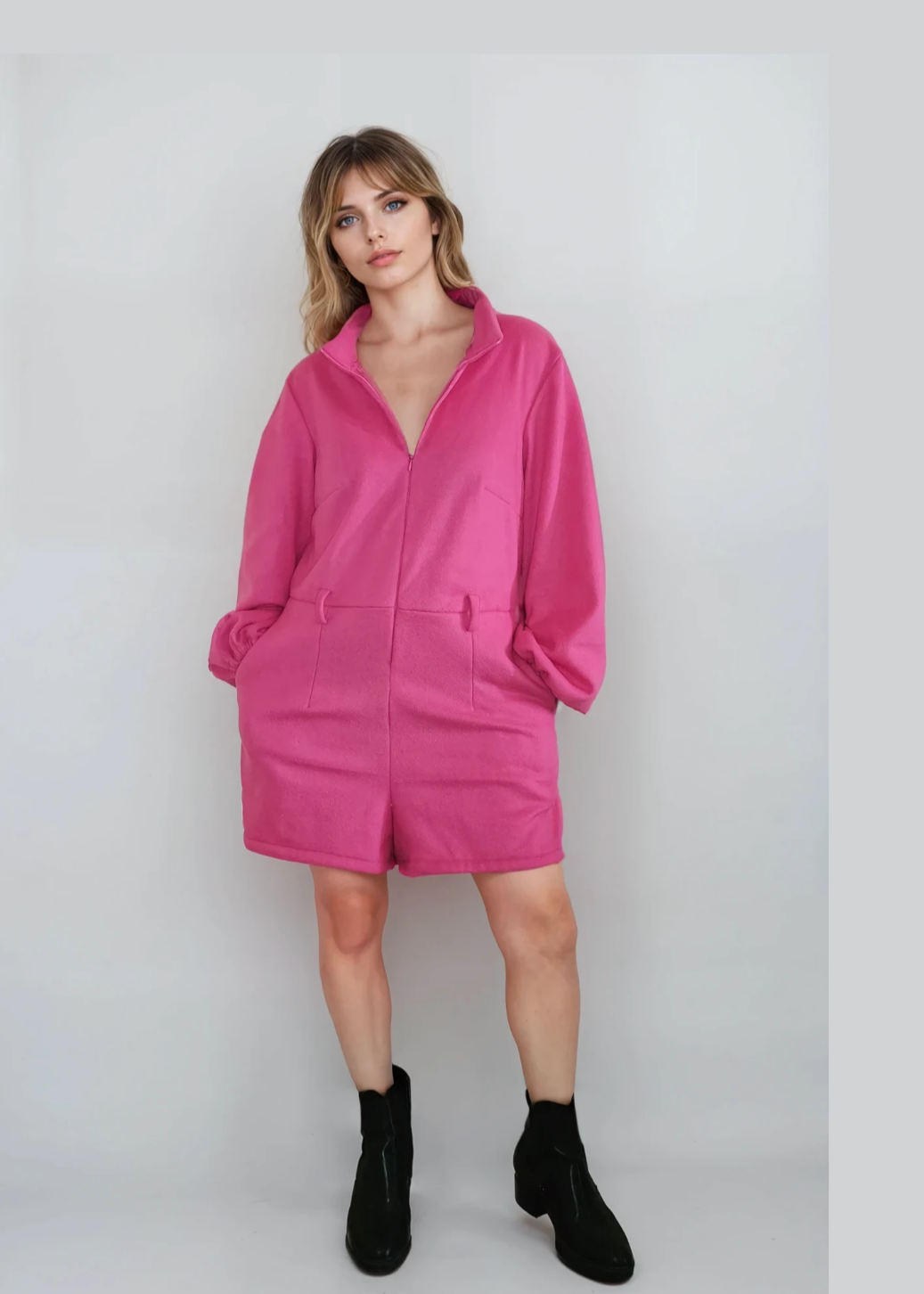 Woman wearing a bright pink zip-up jumpsuit on a white background