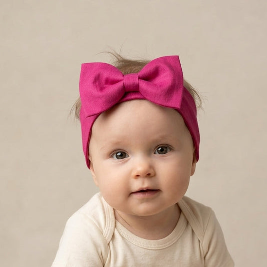 Baby wearing a pink headband with a bow.