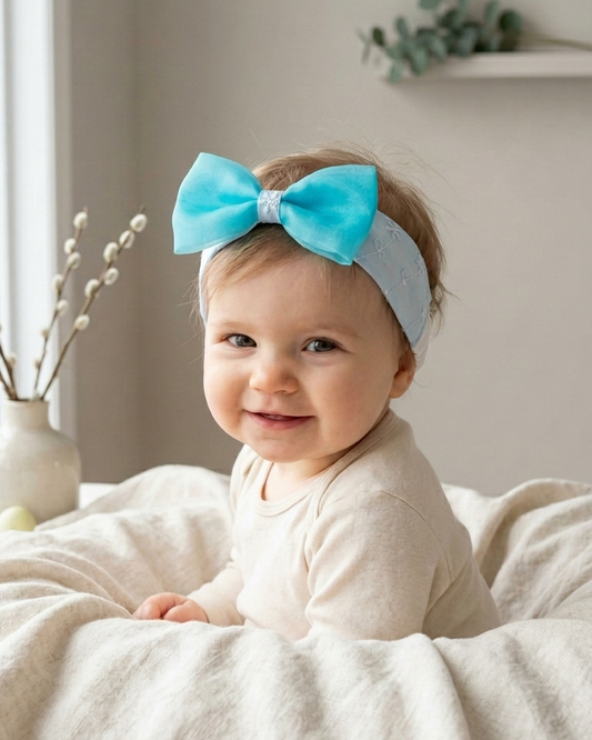 Baby wearing a turquoise bow headband in a cozy indoor setting