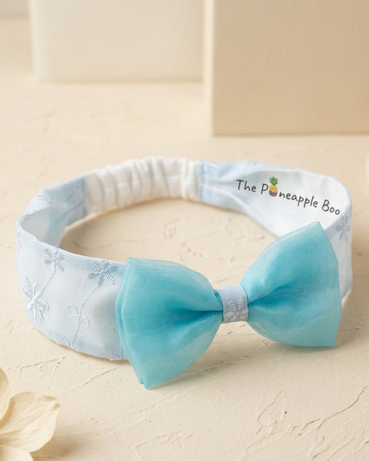 Baby headband with a turquoise bow on a beige background