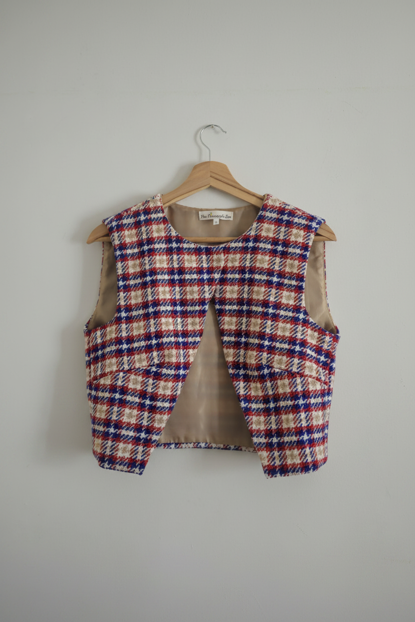 Plaid vest on a hanger against a plain background